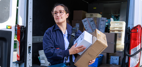 Postal employee unloading packages from a delivery van.